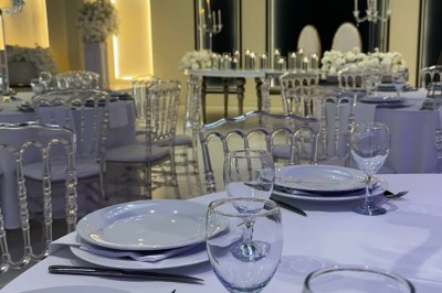 Table de mariage décorée de fleurs blanches et roses, avec deux chaises et un panneau ’Mr & Mrs’ au centre.