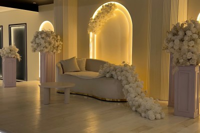 Table de mariage décorée de fleurs blanches et roses, avec deux chaises et un panneau ’Mr & Mrs’ au centre.