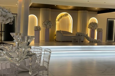 Table de mariage décorée de fleurs blanches et roses, avec deux chaises et un panneau ’Mr & Mrs’ au centre.