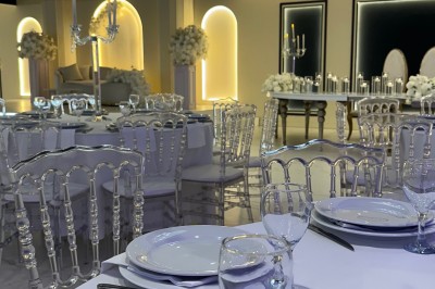 Table de mariage décorée de fleurs blanches et roses, avec deux chaises et un panneau ’Mr & Mrs’ au centre.