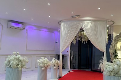 Table de mariage décorée de fleurs blanches et roses, avec deux chaises et un panneau ’Mr & Mrs’ au centre.