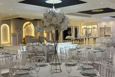 Table de mariage décorée de fleurs blanches et roses, avec deux chaises et un panneau ’Mr & Mrs’ au centre.