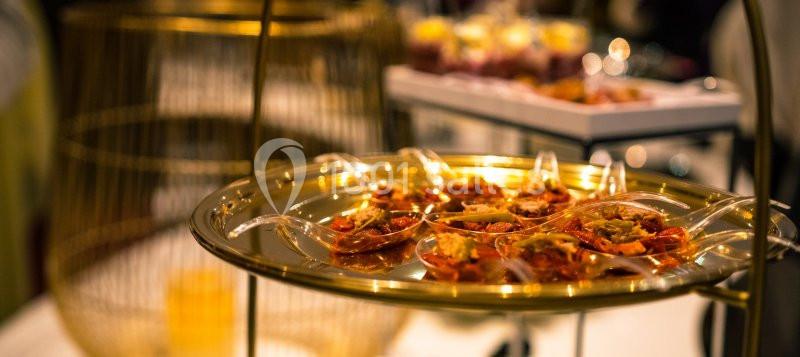 Des cuillères transparentes contenant des bouchées apéritives sont disposées sur un plateau doré.