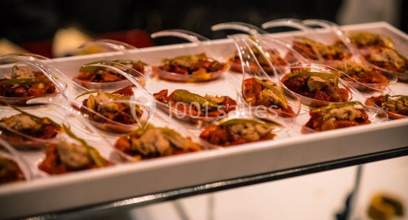 Plateau de petites portions de nourriture servies dans des cuillères transparentes, disposées en rangées.