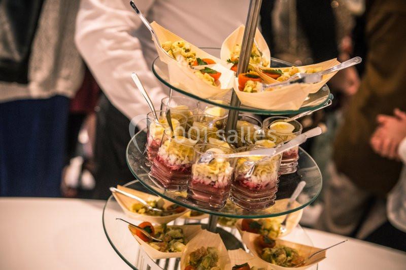 Plateau de verrines et amuse-bouches disposés sur un présentoir en verre lors d'un événement.