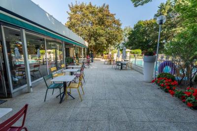 Chambre avec un lit double, un canapé gris, un mur clair et un tableau encadré.