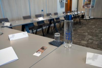 Chambre avec un lit double, un canapé gris, un mur clair et un tableau encadré.