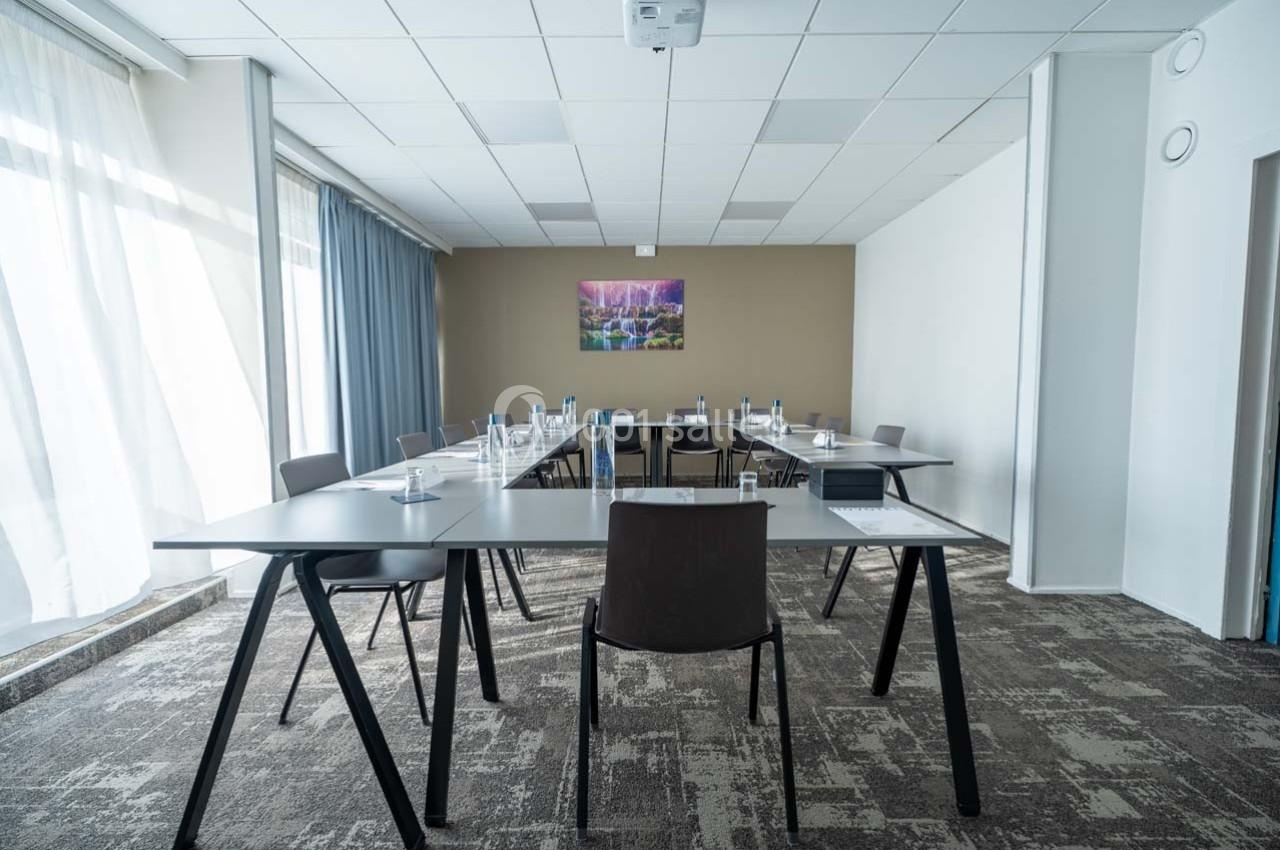 Salle de réunion lumineuse avec tables en triangle, chaises modernes, et un tableau mural coloré.