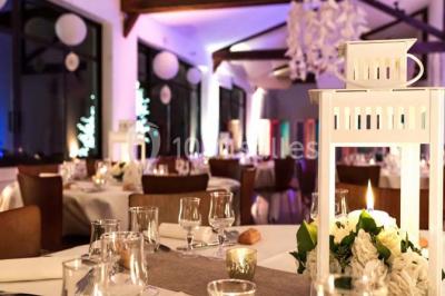 Groupe de personnes réunies en extérieur sous une structure métallique, devant un bâtiment en pierre et bois.