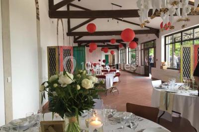 Groupe de personnes réunies en extérieur sous une structure métallique, devant un bâtiment en pierre et bois.