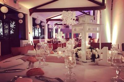 Groupe de personnes réunies en extérieur sous une structure métallique, devant un bâtiment en pierre et bois.