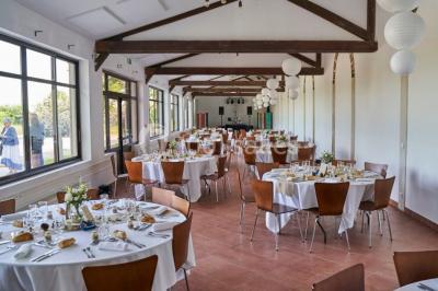 Groupe de personnes réunies en extérieur sous une structure métallique, devant un bâtiment en pierre et bois.