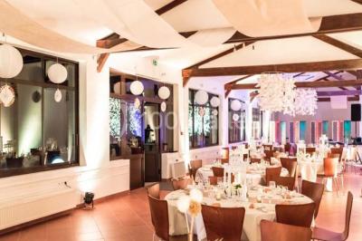 Bâtiment éclairé avec des fenêtres rouges, arbres décorés de lumières blanches et allée pavée de nuit.