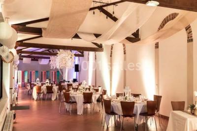 Bâtiment éclairé avec des fenêtres rouges, arbres décorés de lumières blanches et allée pavée de nuit.