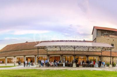 Bâtiment éclairé avec des fenêtres rouges, arbres décorés de lumières blanches et allée pavée de nuit.