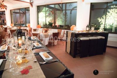 Bâtiment éclairé avec des fenêtres rouges, arbres décorés de lumières blanches et allée pavée de nuit.
