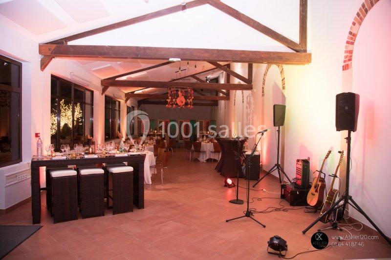 Salle de réception décorée avec des tables dressées, guitares posées au sol et éclairage chaleureux.