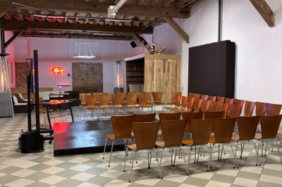 Salle de réunion avec une grande table rectangulaire, chaises noires, documents, bouteilles d'eau et écran de présentation.