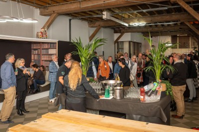 Salle de réunion avec une grande table rectangulaire, chaises noires, documents, bouteilles d'eau et écran de présentation.