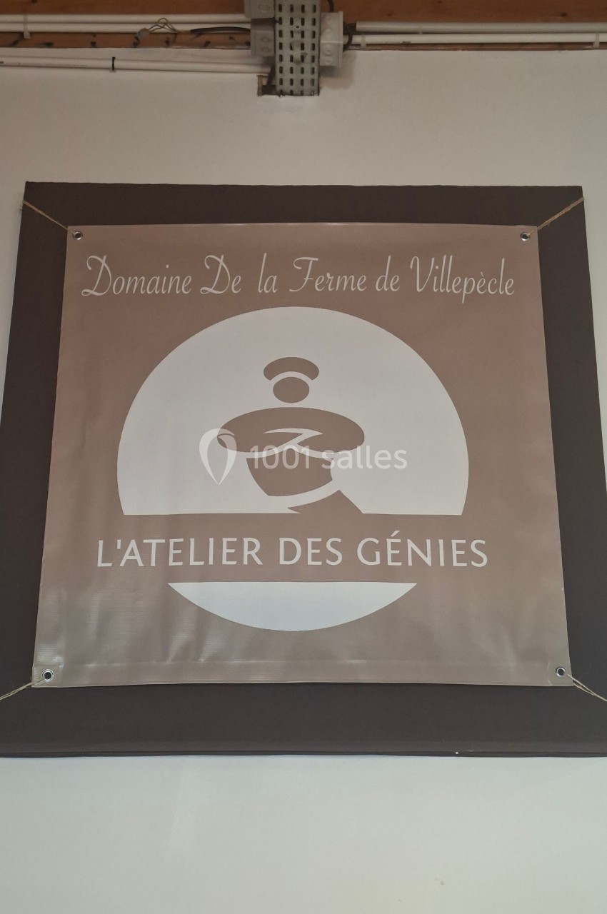Panneau mural indiquant ’Domaine de la Ferme de Villepècle - L'Atelier des Génies’ avec un logo stylisé.