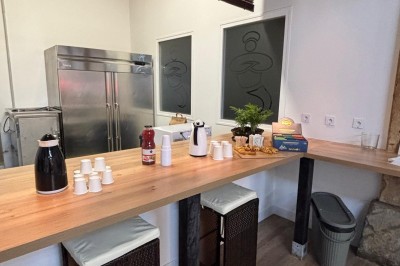 Salle de réunion avec une grande table rectangulaire, chaises noires, documents, bouteilles d'eau et écran de présentation.