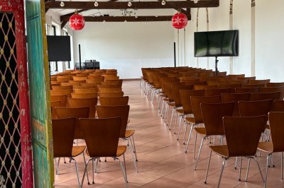 Salle de réunion avec une grande table rectangulaire, chaises noires, documents, bouteilles d'eau et écran de présentation.