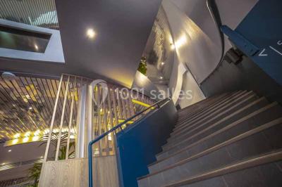 Miniature Location salle Villejuif (Val-de-Marne) - Espace Evénementiel Les Esselières - Paris Sud #1 Entrée d'un bâtiment avec escalier central, écrans d'affichage, plantes décoratives et sol en parquet.