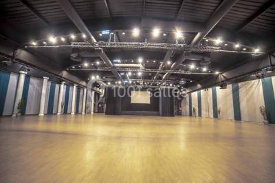 Miniature Salle Capella Entrée d'un bâtiment avec escalier central, écrans d'affichage, plantes décoratives et sol en parquet.