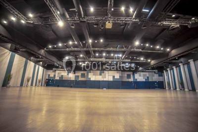Miniature Salle Capella Entrée d'un bâtiment avec escalier central, écrans d'affichage, plantes décoratives et sol en parquet.