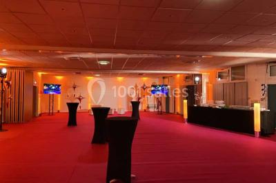 Miniature Salles du RDC modulables Entrée d'un bâtiment avec escalier central, écrans d'affichage, plantes décoratives et sol en parquet.