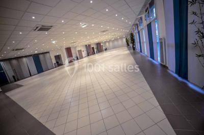 Miniature Salles du RDC modulables Entrée d'un bâtiment avec escalier central, écrans d'affichage, plantes décoratives et sol en parquet.