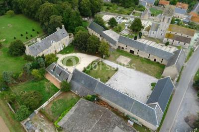 Vue nocturne d'une porte monumentale en pierre éclairée, avec un bâtiment blanc visible en arrière-plan.