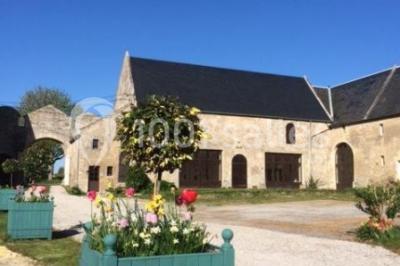 Vue nocturne d'une porte monumentale en pierre éclairée, avec un bâtiment blanc visible en arrière-plan.