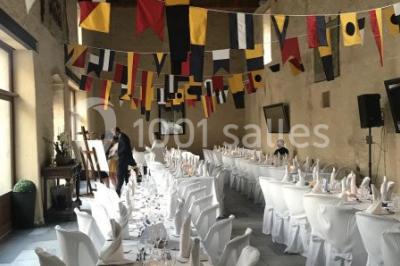 Vue nocturne d'une porte monumentale en pierre éclairée, avec un bâtiment blanc visible en arrière-plan.