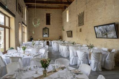 Vue nocturne d'une porte monumentale en pierre éclairée, avec un bâtiment blanc visible en arrière-plan.