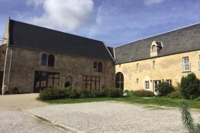 Vue nocturne d'une porte monumentale en pierre éclairée, avec un bâtiment blanc visible en arrière-plan.