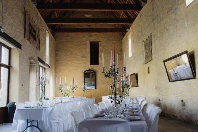 Vue nocturne d'une porte monumentale en pierre éclairée, avec un bâtiment blanc visible en arrière-plan.