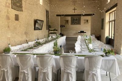 Vue nocturne d'une porte monumentale en pierre éclairée, avec un bâtiment blanc visible en arrière-plan.