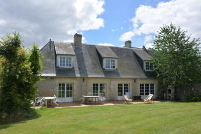 Vue nocturne d'une porte monumentale en pierre éclairée, avec un bâtiment blanc visible en arrière-plan.
