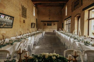 Vue nocturne d'une porte monumentale en pierre éclairée, avec un bâtiment blanc visible en arrière-plan.