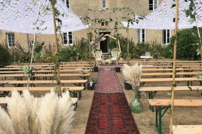 Vue nocturne d'une porte monumentale en pierre éclairée, avec un bâtiment blanc visible en arrière-plan.