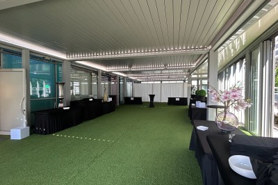 Miniature Location salle Villeurbanne (Rhône) - Le Pavillon De La Soie #29 Terrasse avec pergola en bois, tables et chaises noires, sol en bois et gazon artificiel, ciel bleu en arrière-plan.