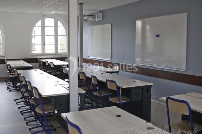 Terrasse extérieure avec des tables rondes et des chaises rouges et noires, entourée de végétation et de barrières…