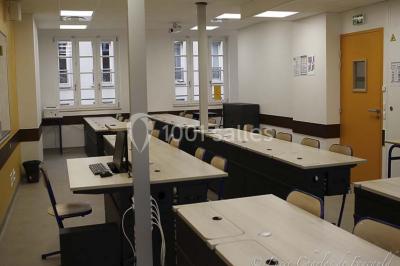 Terrasse extérieure avec des tables rondes et des chaises rouges et noires, entourée de végétation et de barrières…