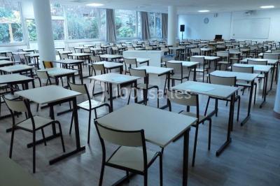 Terrasse extérieure avec des tables rondes et des chaises rouges et noires, entourée de végétation et de barrières…