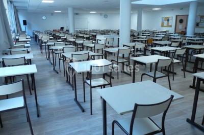 Terrasse extérieure avec des tables rondes et des chaises rouges et noires, entourée de végétation et de barrières…