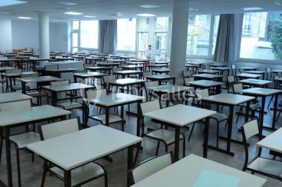 Terrasse extérieure avec des tables rondes et des chaises rouges et noires, entourée de végétation et de barrières…