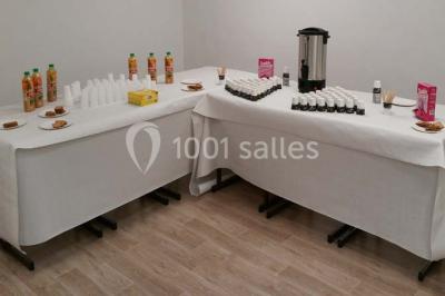 Terrasse extérieure avec des tables rondes et des chaises rouges et noires, entourée de végétation et de barrières…