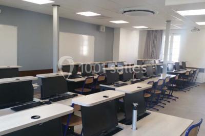 Terrasse extérieure avec des tables rondes et des chaises rouges et noires, entourée de végétation et de barrières…