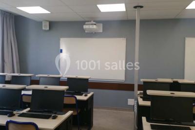 Terrasse extérieure avec des tables rondes et des chaises rouges et noires, entourée de végétation et de barrières…